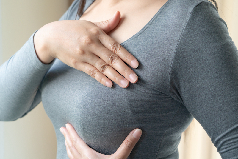 Woman hand checking lumps on her breast for signs of breast cancer. Women healthcare concept.